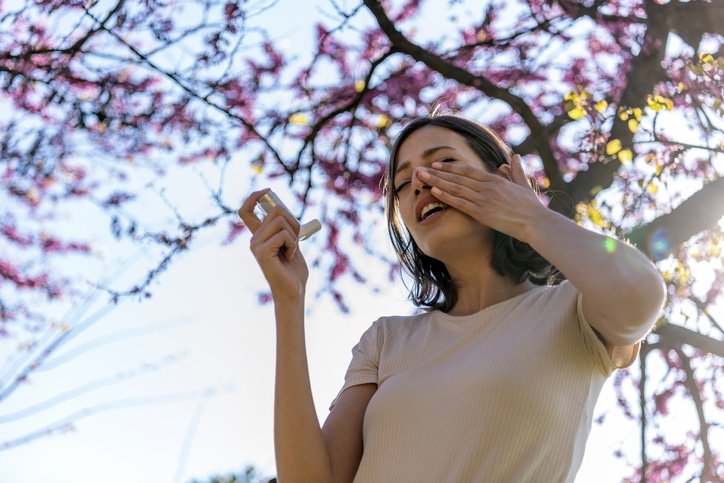 Asthmatic Woman Suffers From Asthma and is Using Inhaler in the Public Park. Chronic Disease Control, Allergy Induced Asthma Remedy and Chronic Pulmonary Disease Concept.