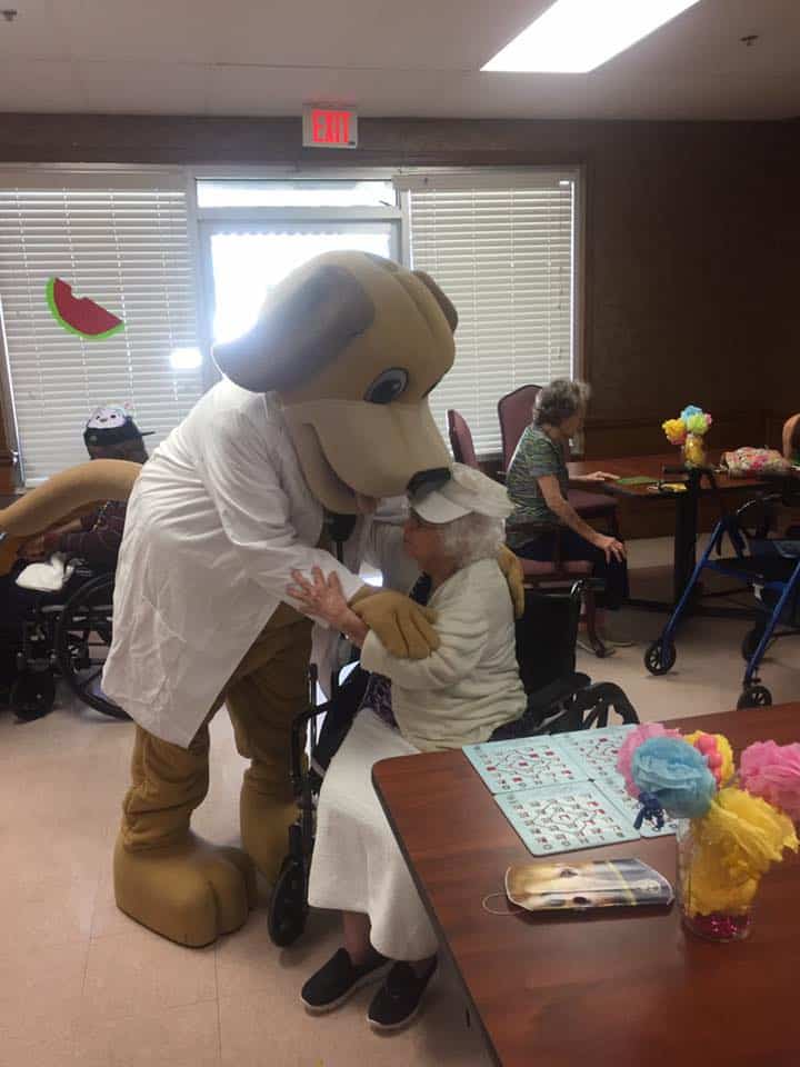 MainStreet mascot hugs lady in white shirt and white hat at bingo