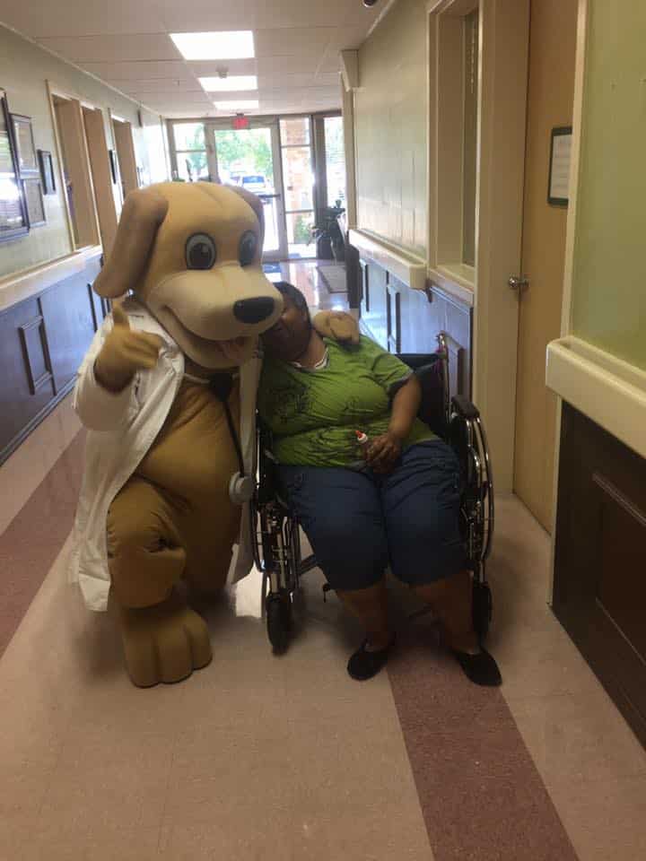 MainStreet Mascot hugs elderly lady in green shirt