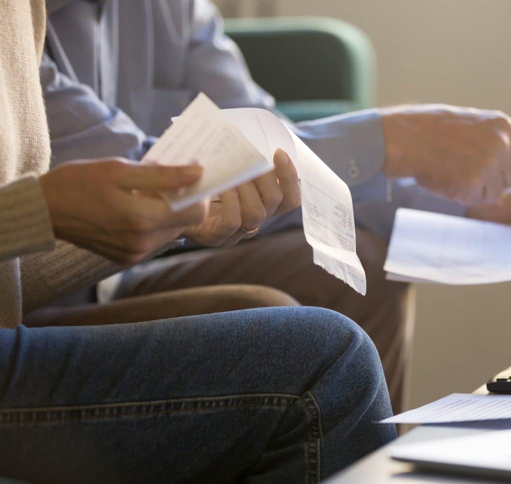 man and woman holding bills going through tough times