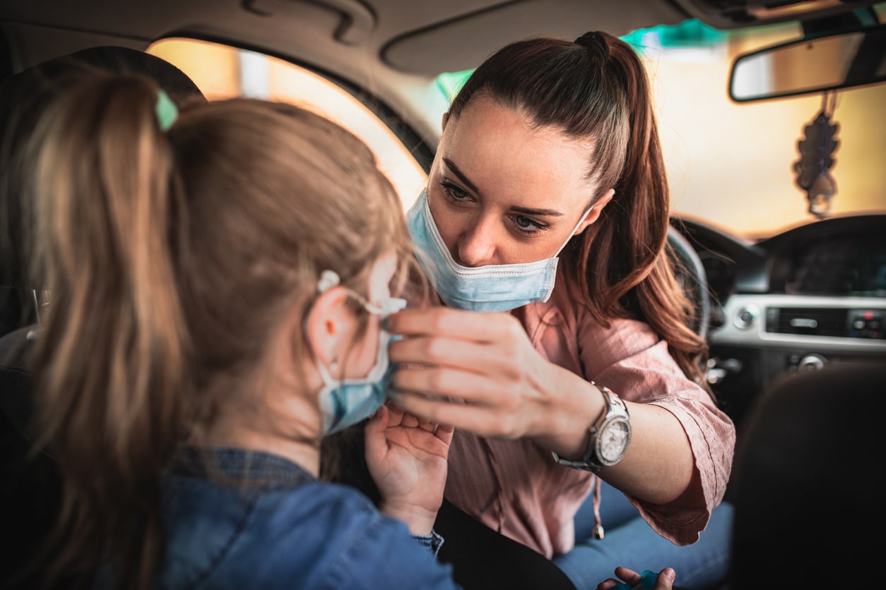 Woman in protective mask driving a car on road