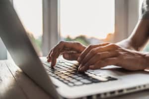 Men is typing on laptop computer keyboard looking for portal support