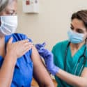 Nurse gives senior adult healthcare worker the Covid-19 vaccine