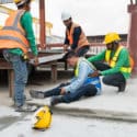 Men working and a man with workers compensation injuries on the ground