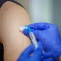 Vaccine injection. Syringe with medicine in the hands of a doctor in blue gloves.