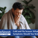 Man sneezing on a couch. Featured image for Cold and Flu Season: What Symptoms Should You Watch For? blog post