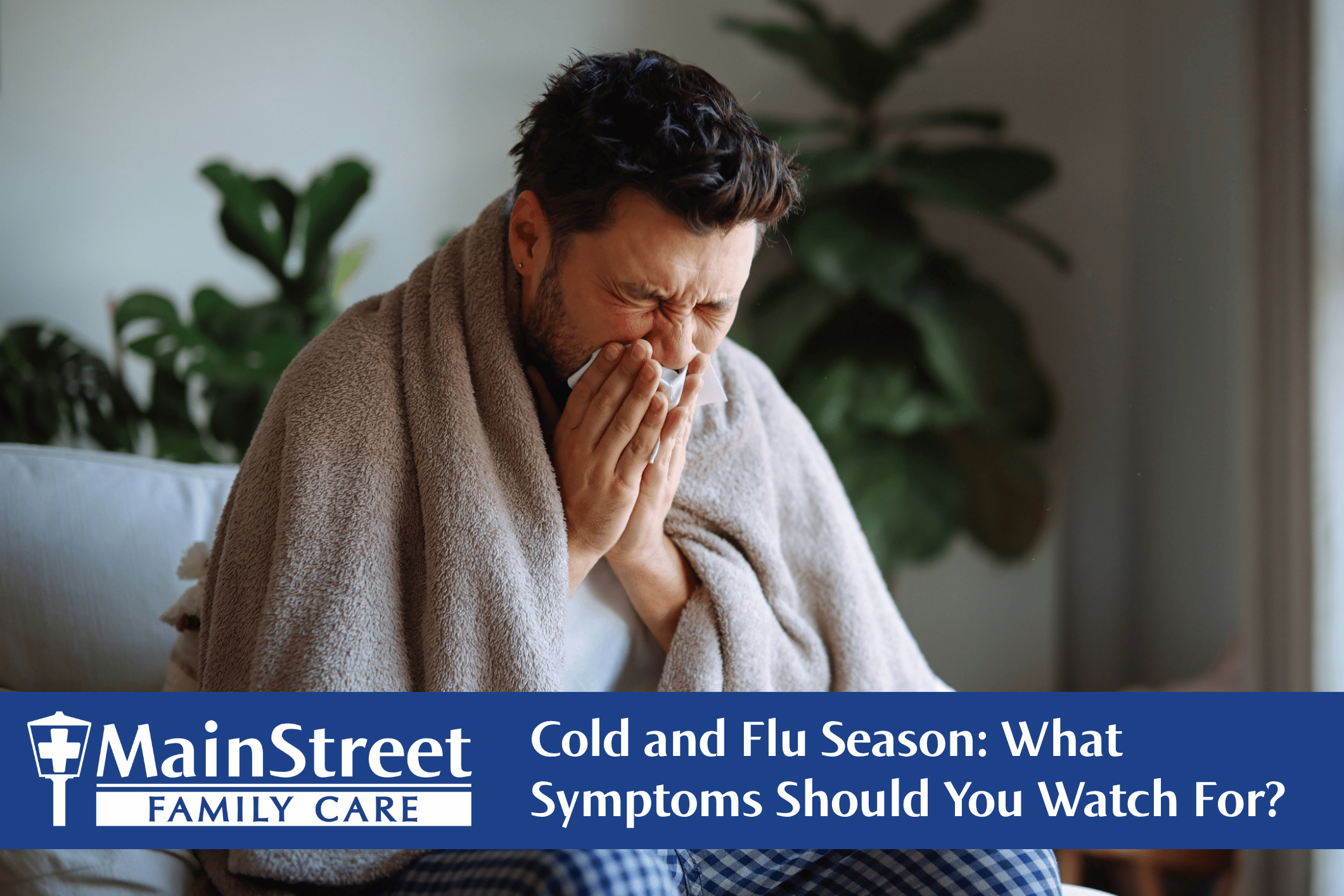 Man sneezing on a couch. Featured image for Cold and Flu Season: What Symptoms Should You Watch For? blog post