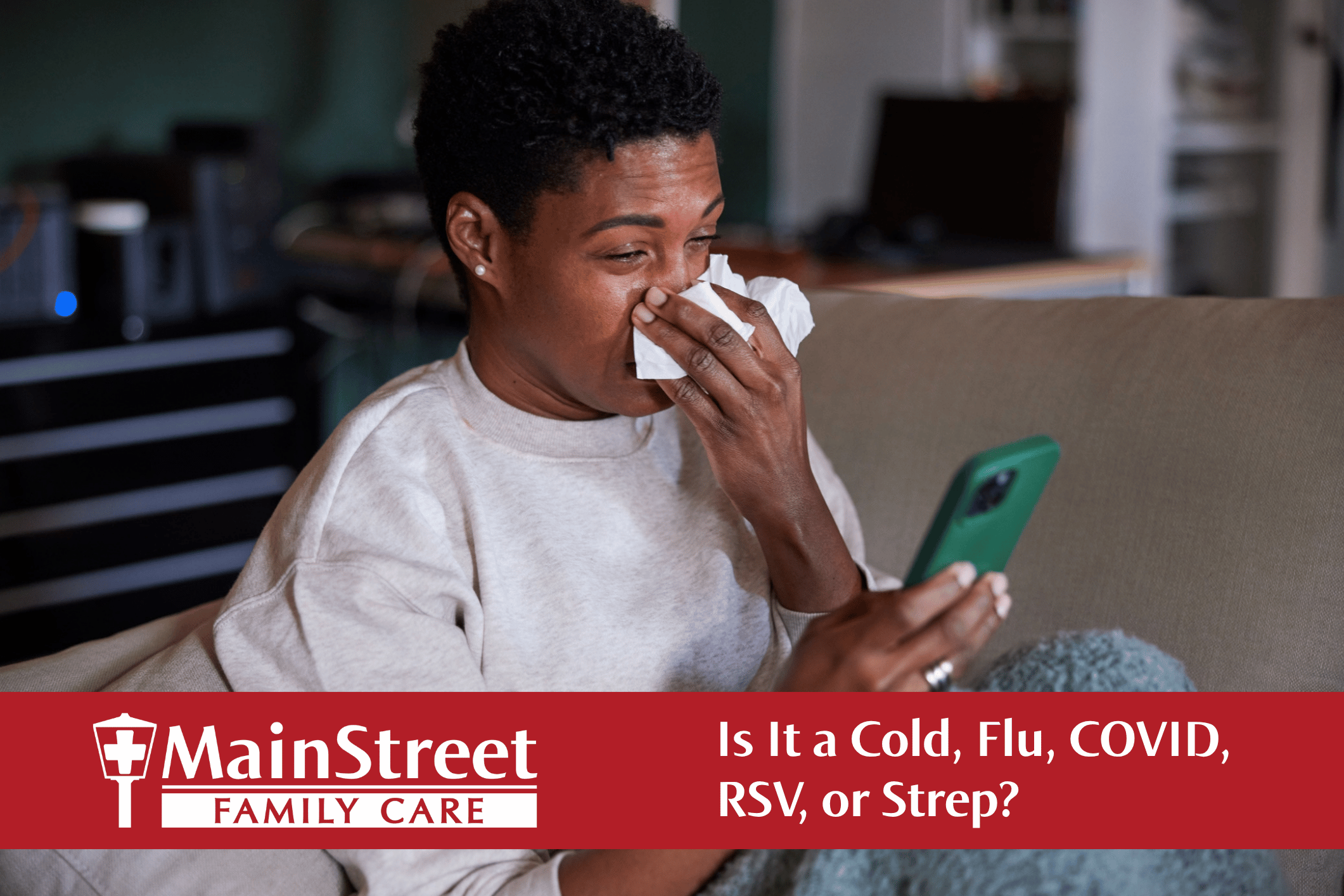 Person sneezing on their couch while looking at their cell phone. Featured image for Is It a Cold, Flu, COVID, RSV, or Strep? blog post